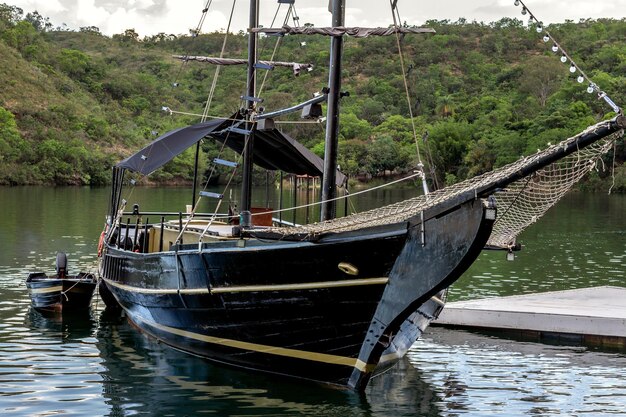 Photo close up of a boat schooner moored at the pier on a tranquil lake with mountains in the background