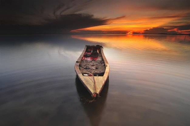 Close-up of boat in sea against sunset sky
