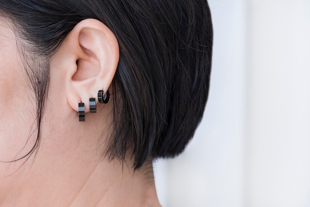 Close up of Bob hair woman wearing 3 black stainless steel earrings on white background