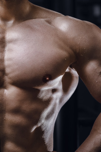 Foto primo piano del corpo dell'uomo atletico in palestra fitness bodybuilding e concetto di sport