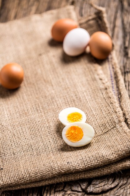 Close-up boiled or raw chicken eggs on wooden board.