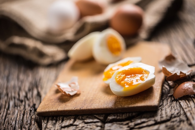 Close-up boiled or raw chicken eggs on wooden board.