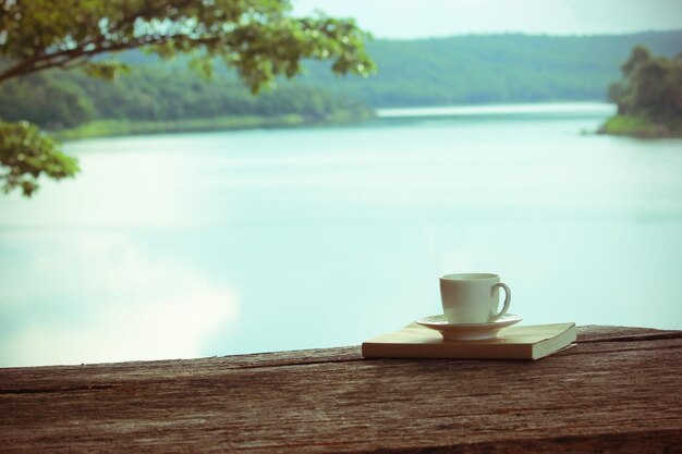 Foto close-up di un libro e una tazza di caffè al lago