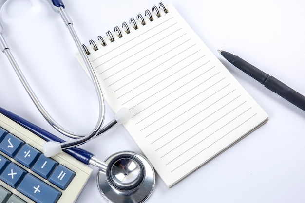 Photo close-up of book with stethoscope and calculator on table