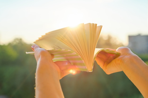 Primo piano del libro in mano della donna, tramonto di sfondo