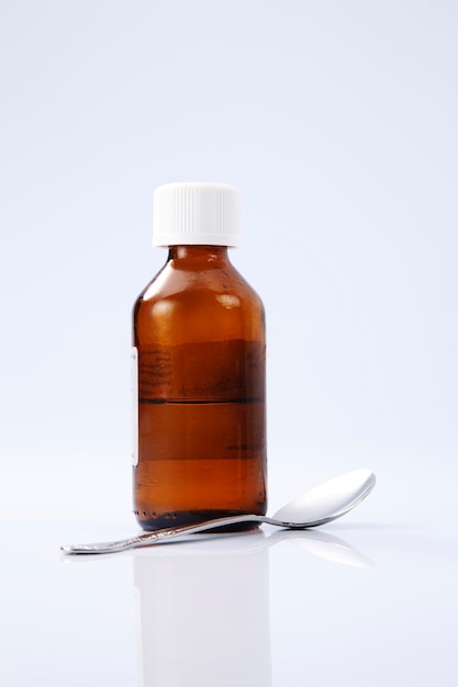 close-up of bottle and spoon against white background