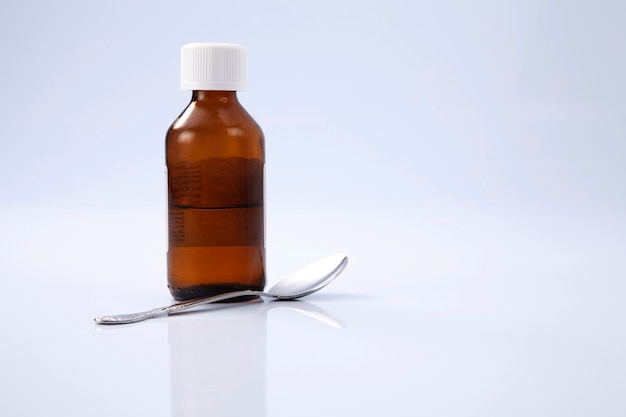 close-up of bottle and spoon against white background