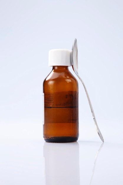 close-up of bottle and spoon against white background