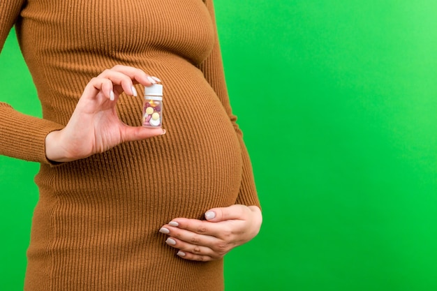 Close up of a bottle of vitamin pills in pregnant woman's hand at colorful background with copy space Healthcare concept