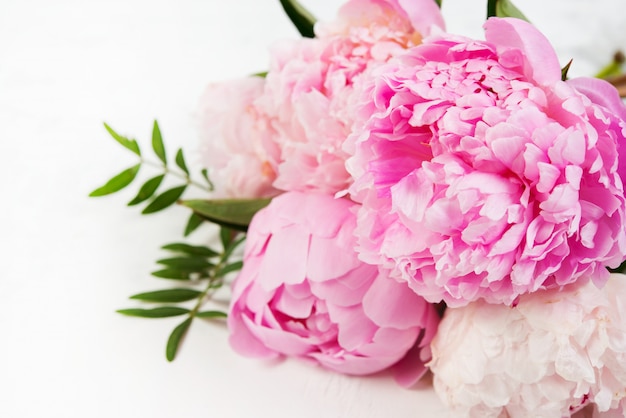 Close up bouquet of fresh beautiful flowers lies on a white background. Pink peonies lie on the right . Horizontal photo