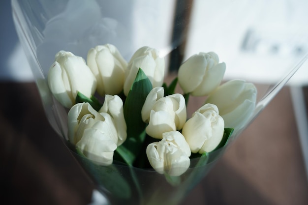 Close-up of a bouquet of white tulips. White tulips lie in a decorative white wicker basket