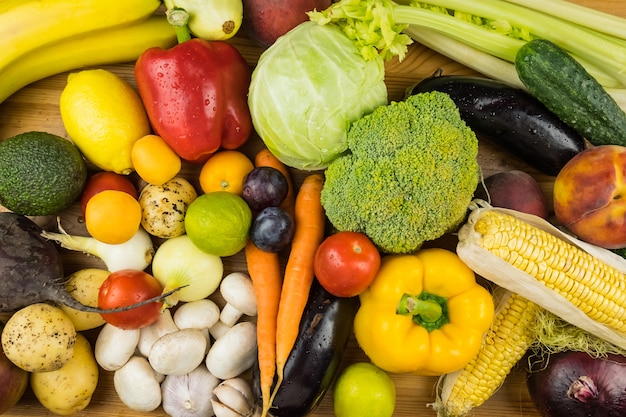 Close-up bovenaanzicht beeld van verse biologische groenten en fruit. Lokaal geteelde paprika, maïs, wortel, champignons en ander natuurlijk veganistisch eten op tafel.