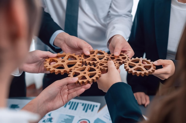 Close-up bovenaanzicht handen met tandwielen boven tafel met BI-rapporten voor harmonie