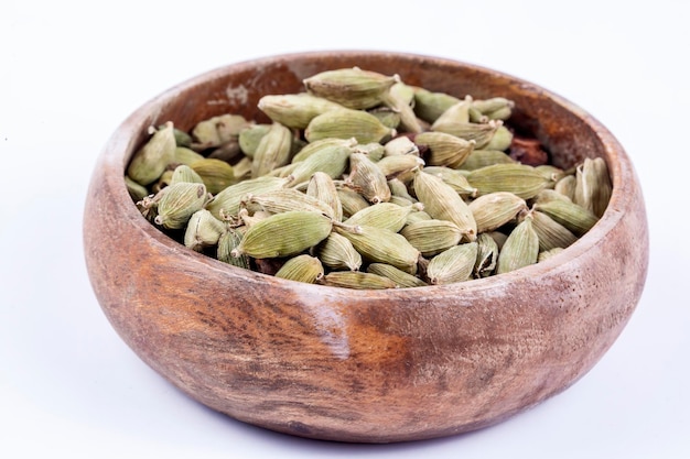 Close-up bovenaanzicht van gedroogde groene Elettaria cardamomum vruchten met zaden, kardemom spice verspreid op witte achtergrond