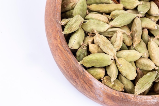 Close-up bovenaanzicht van gedroogde groene Elettaria cardamomum vruchten met zaden, kardemom spice verspreid op witte achtergrond