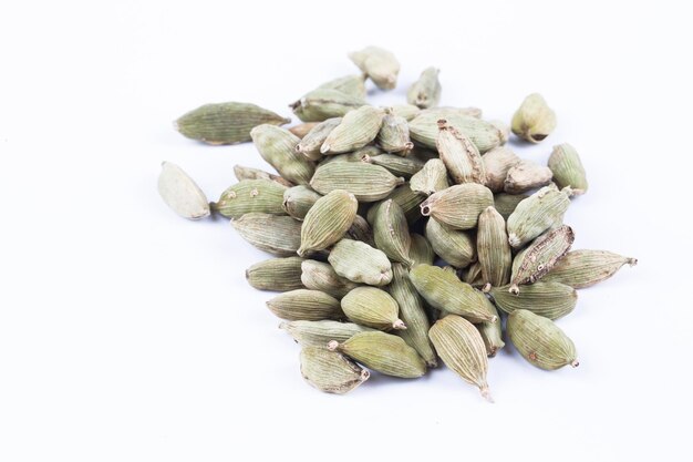 Close-up bovenaanzicht van gedroogde groene Elettaria cardamomum vruchten met zaden, kardemom spice verspreid op witte achtergrond