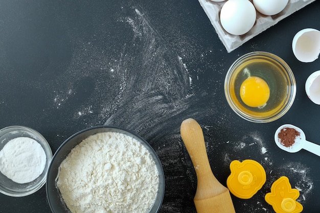 Close-up bovenaanzicht van ingrediënten en keukengerei voor het bakken van een taart en op een zwarte achtergrond. horizontale oriëntatie, selectieve aandacht.