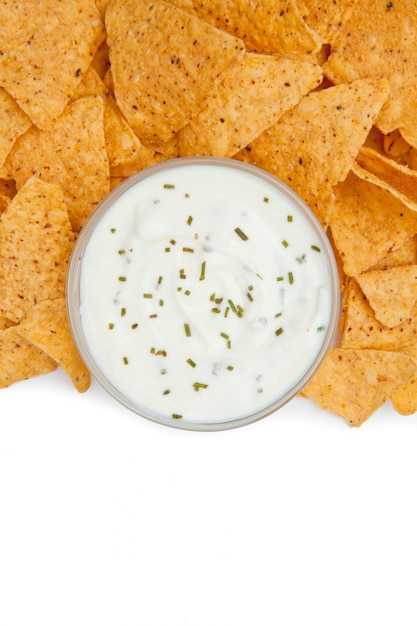 Photo close up of a bowl of dip with herbs surrounded by nachos