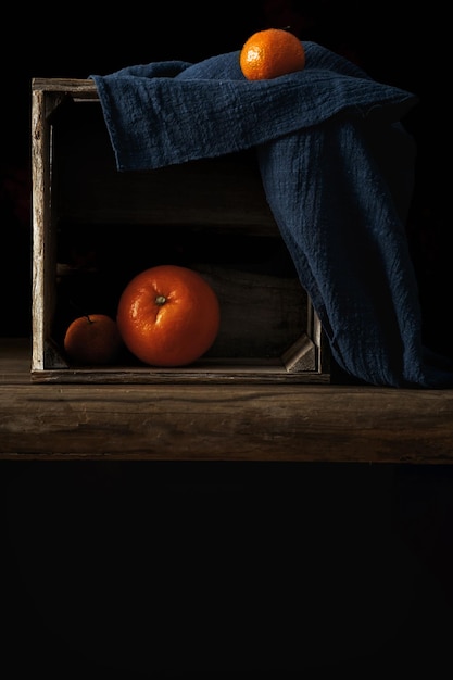 A close up of a box with oranges and a blue cloth