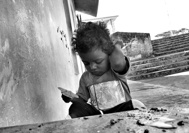 Photo close-up of boy crouching by wall