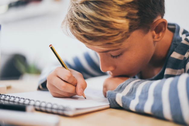 Close-up of boy drawing in note pad at table