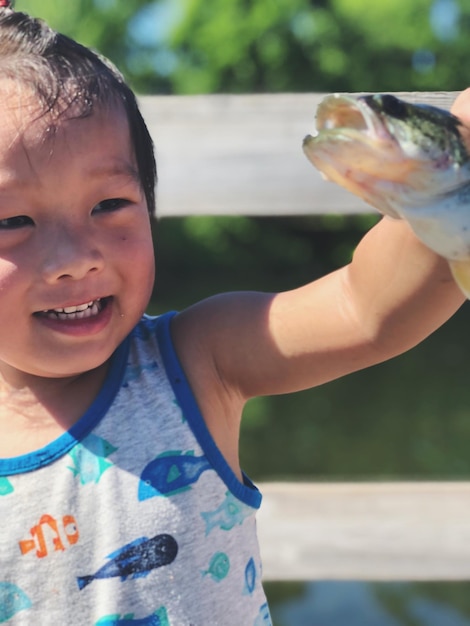 湖で魚を握っている少年をクローズアップ