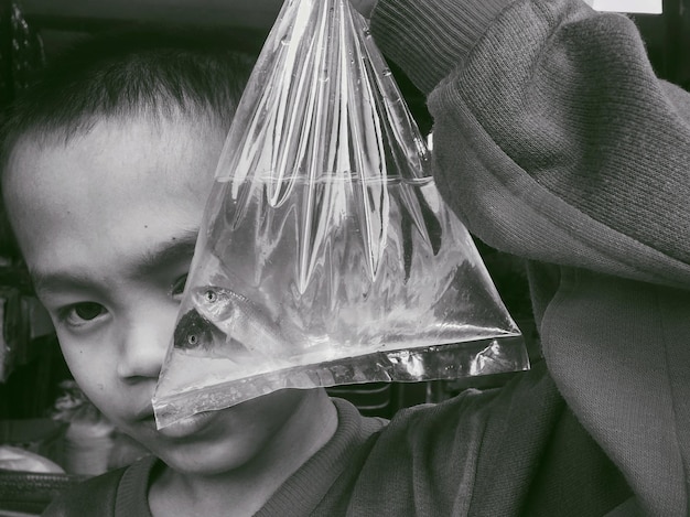 Foto close-up di un ragazzo che tiene dei pesci in un sacchetto di plastica