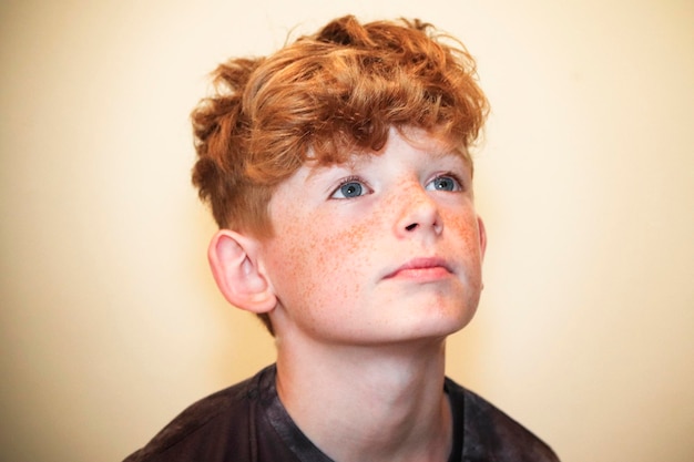 Photo close-up of boy looking away against beige wall