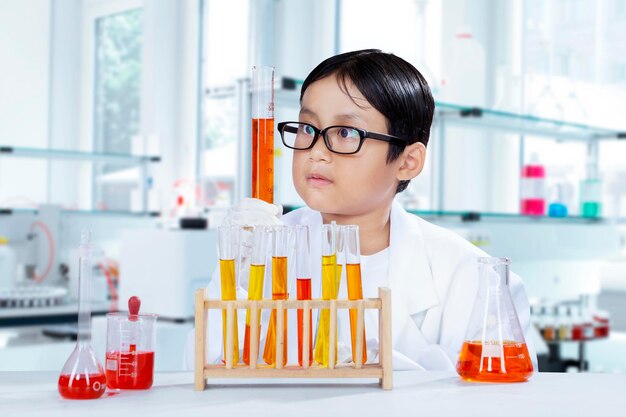 Close-up of boy looking at chemical in test tube against blue background