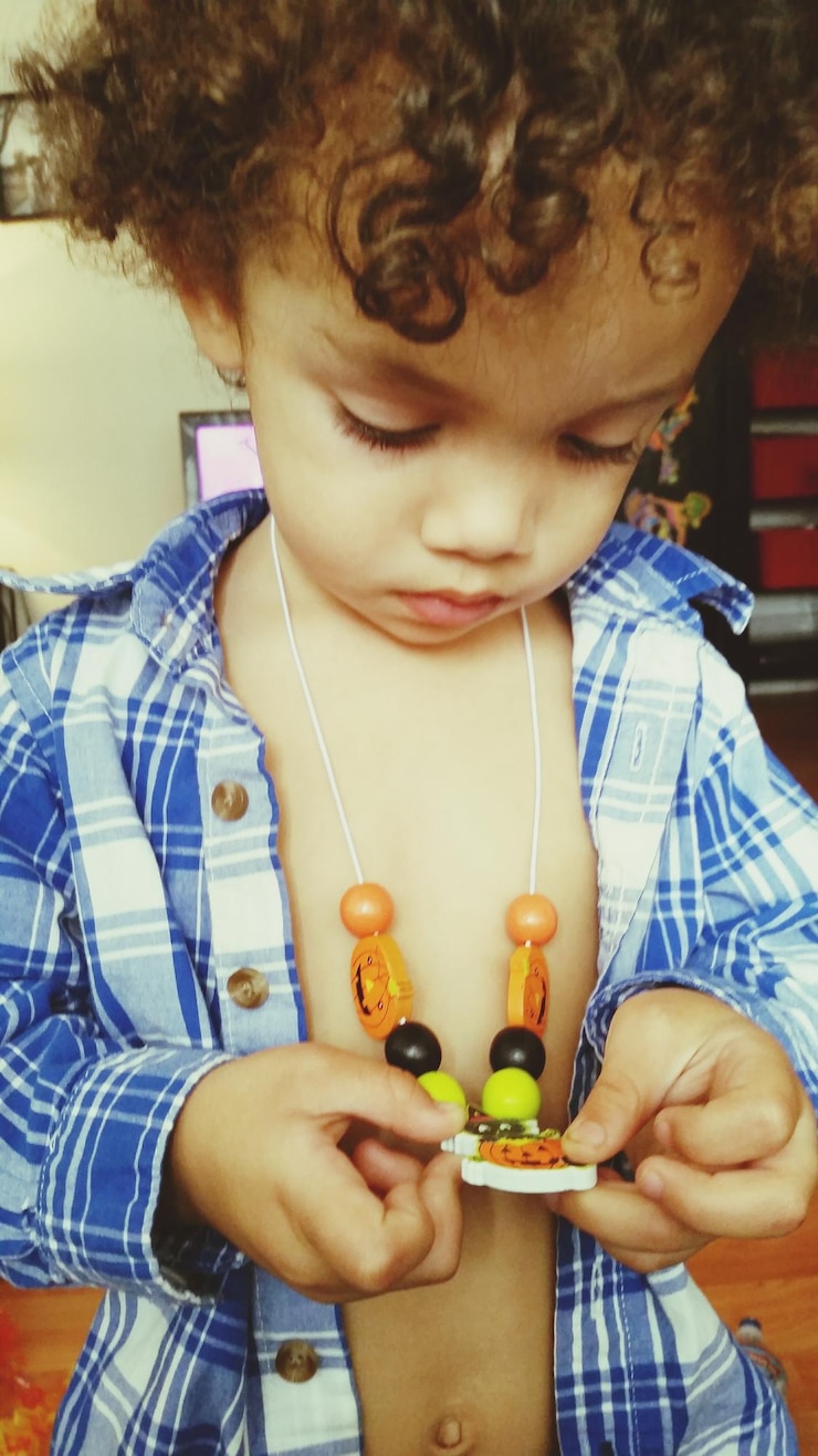 Photo close-up of boy looking at necklace while standing at home