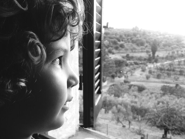 Photo close-up of boy looking through window