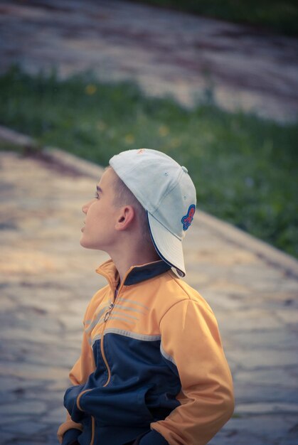 Photo close-up of boy looking up while standing on footpath