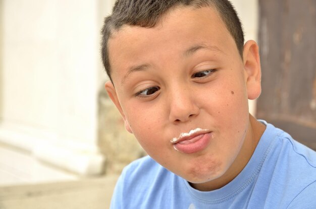 Foto close-up di un ragazzo che fa la faccia con i baffi di latte