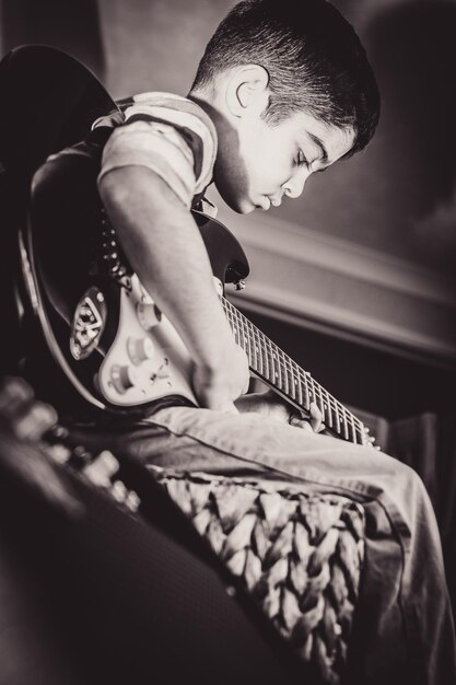 Close-up of boy playing guitar at home