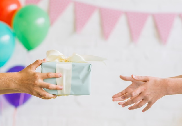 Foto primo piano della mano di un ragazzo che dà regalo di compleanno al suo amico