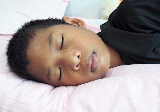 A close up of a boy sleeping on the bed