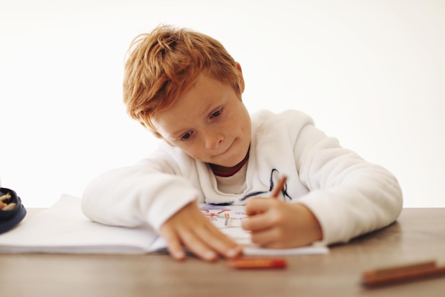 Photo close-up of boy writing on book against white background