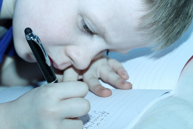 Foto close-up di un ragazzo che scrive in un libro