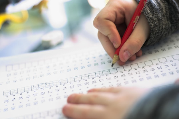 Foto close-up di un ragazzo che scrive su carta al tavolo