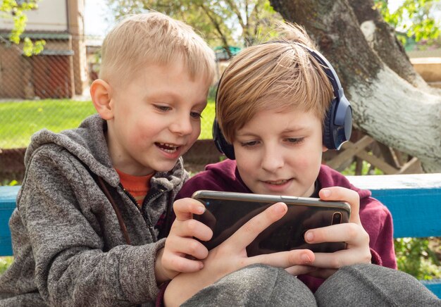 Photo close-up of boys playing video game outdoors