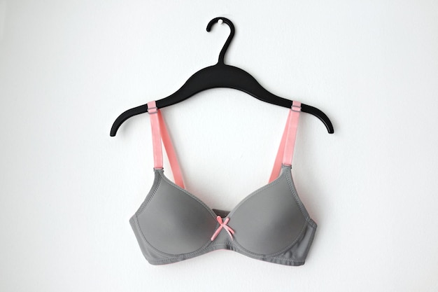 Photo close-up of bra hanging on coathanger against white wall