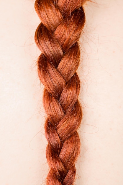 Близкий план плетеных волос на розовом фоне