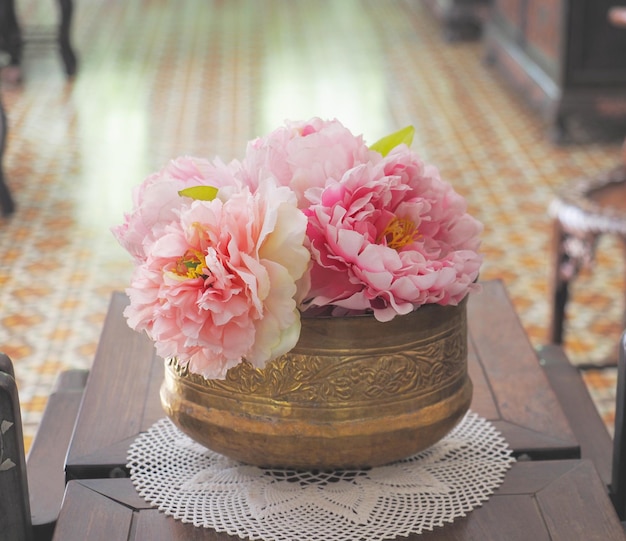 写真 木製のテーブルの上に花が入った真鍮のビンテージ花瓶を閉じます