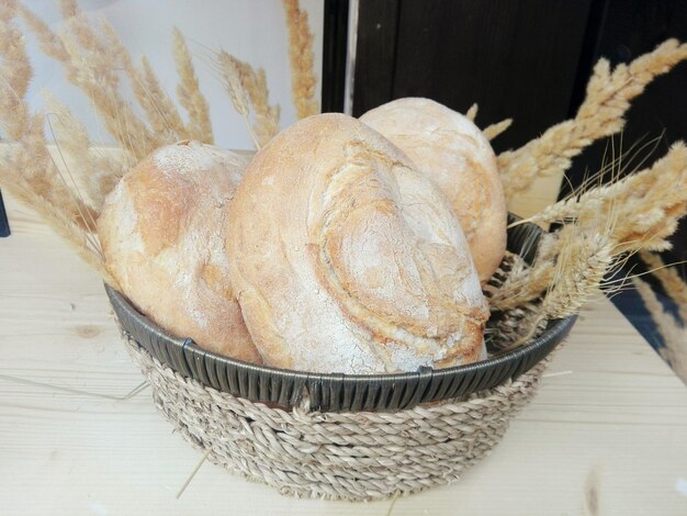 Close-up of breads with wheat in wicker basket on table