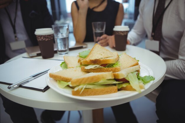 Photo close-up of breakfast on table with businesspeople