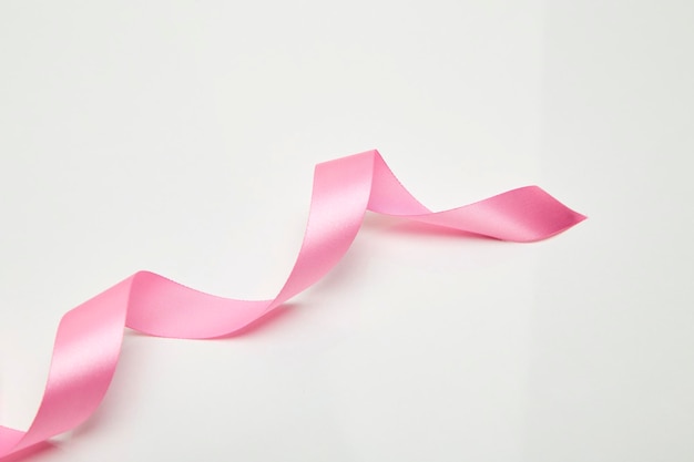 Close-up of breast cancer awareness ribbon over white background