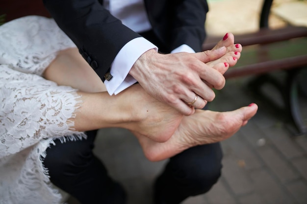 Close up a bride putting her legs on groom Man holding woman's feet on his knees