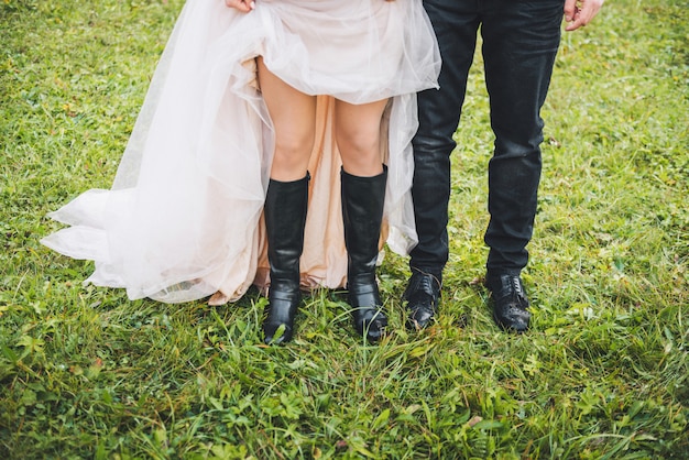 Close up of bride's and groom's legs, standing next to each other on grass