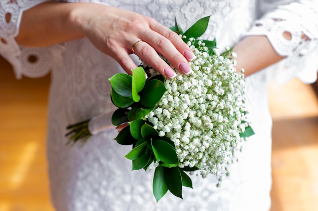 Close up on bride in a white dress holding a wedding bouquet