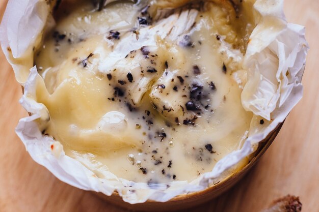 Chiuda sul formaggio brie sul bordo di legno sulla tavola di legno